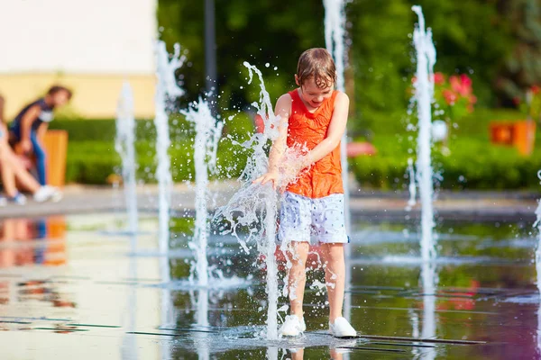 Chico excitado divirtiéndose entre chorros de agua, en la fuente. Verano en la ciudad —  Fotos de Stock