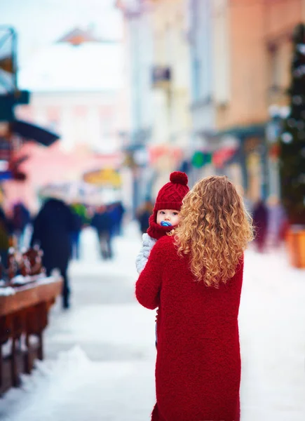 Carino neonato sulla mano della madre sulla strada affollata della città in inverno — Foto Stock