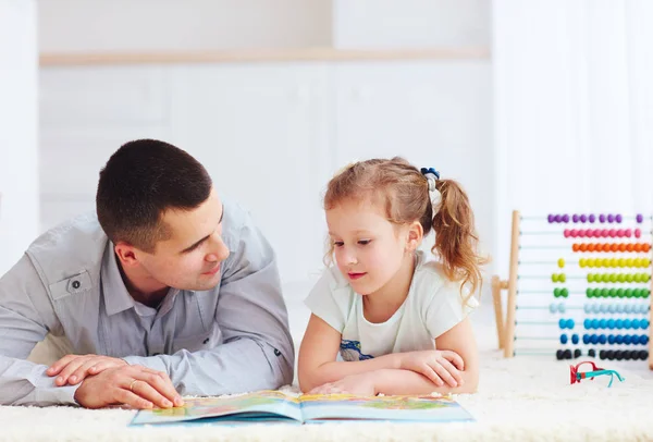Onnellinen isä ja tytär viettää aikaa yhdessä lukemalla mielenkiintoinen kirja — kuvapankkivalokuva
