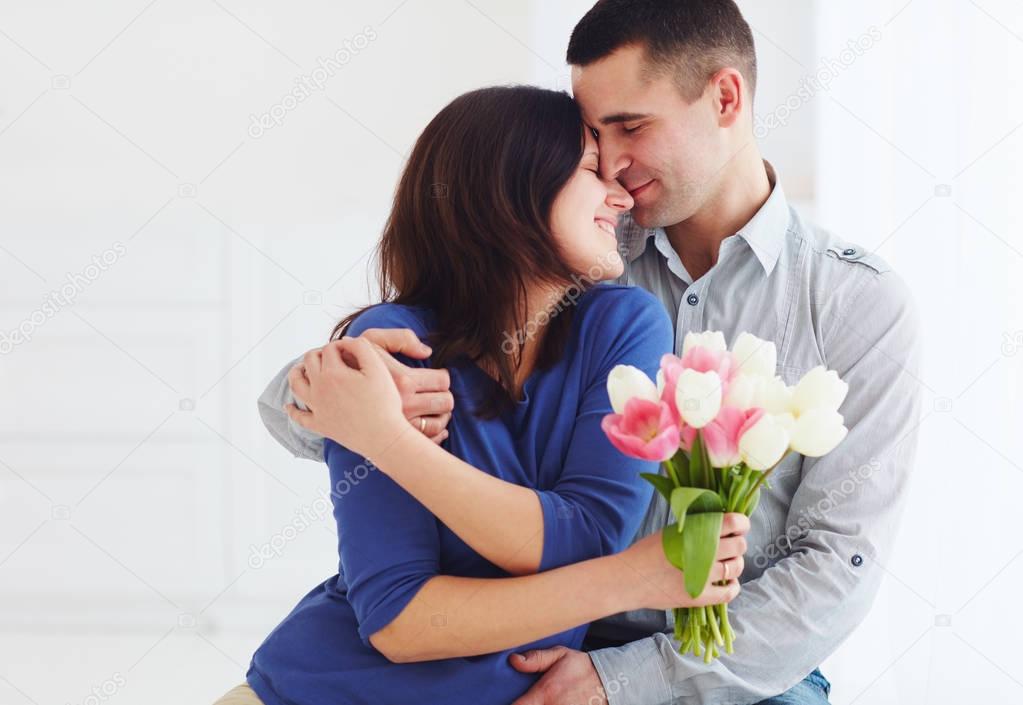 portrait of happy couple, husband and wife with spring flower bouquet