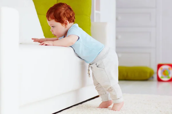 Lindo bebé niño trepando por el sofá en casa — Foto de Stock