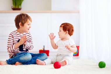 evde genç yürümeye başlayan çocuk kardeşiyle oynayan neşeli kıdemli çocuk