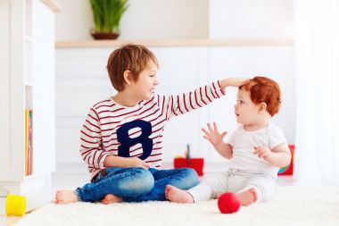 evde genç yürümeye başlayan çocuk kardeşiyle oynayan neşeli kıdemli çocuk