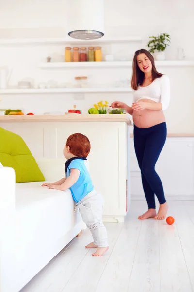 Pregnant young mother looks after infant baby at home — Stock Photo, Image