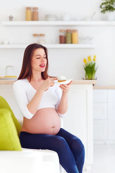 Schöne schwangere Frau isst leckere süße Kuchen zu Hause — Stockfoto