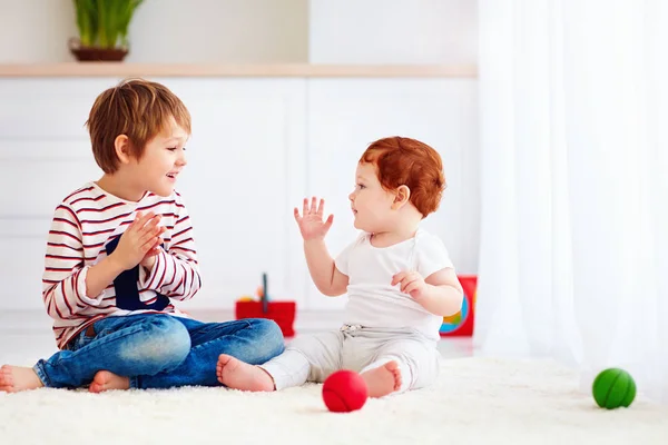 Enfant âgé joyeux jouant avec son petit frère junior à la maison — Photo