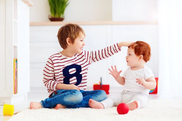 Enfant âgé joyeux jouant avec son petit frère junior à la maison — Photo