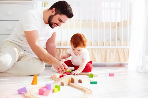 Mutlu baba bebek bebek çocuk ile güneşli çocuk odasında oynarken — Stok fotoğraf