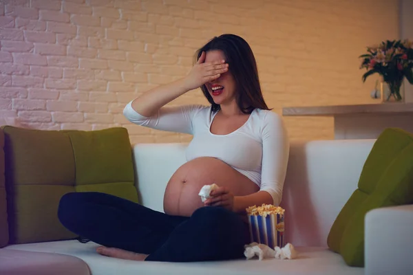 Беременная женщина смотрит фильм ужасов дома одна — стоковое фото