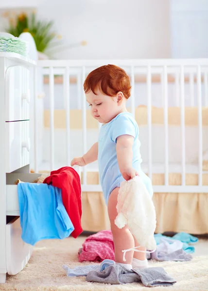 Śmieszne dzieci niemowlę, wyrzucając ubrania z komody w domu — Zdjęcie stockowe