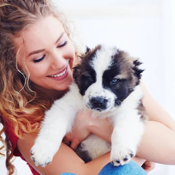 Vacker kvinna leker med söt kaukasiska herde valp, hund — Stockfoto