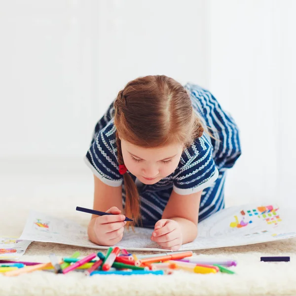 Retrato de desenho bonito menina feliz, enquanto deitado no tapete — Fotografia de Stock