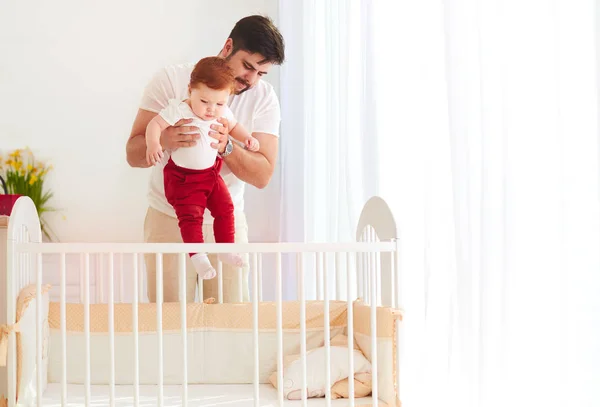 Щасливий батько кладе немовля в ліжечко вдома — стокове фото