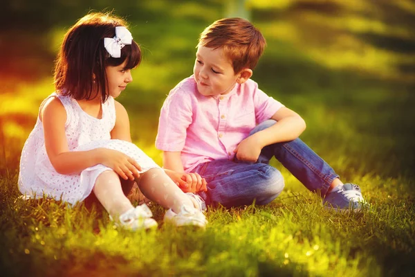 Bambini carini innamorati, seduti insieme nel giardino primaverile — Foto Stock