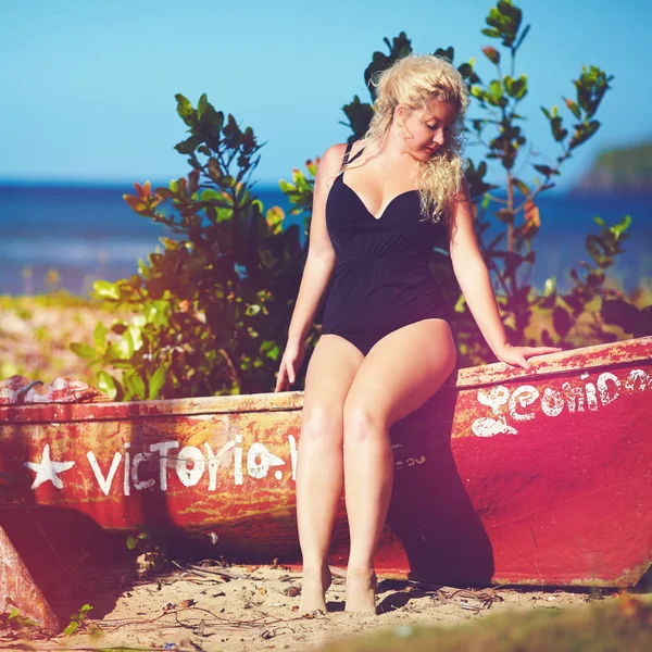 Plus size giovane donna seduta sulla barca sulla spiaggia soleggiata — Foto Stock