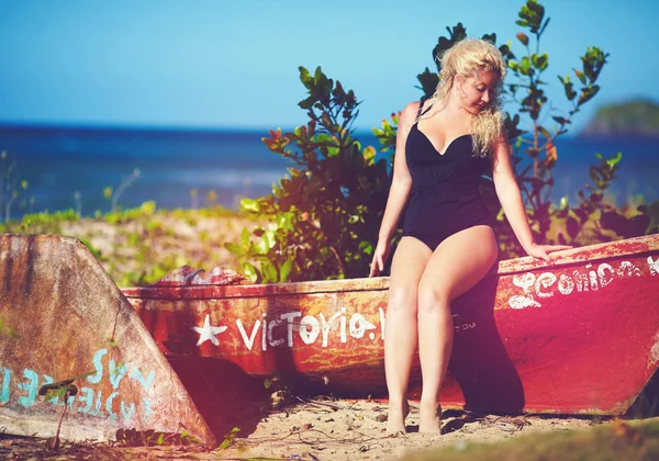 Plus size giovane donna seduta sulla barca sulla spiaggia soleggiata — Foto Stock