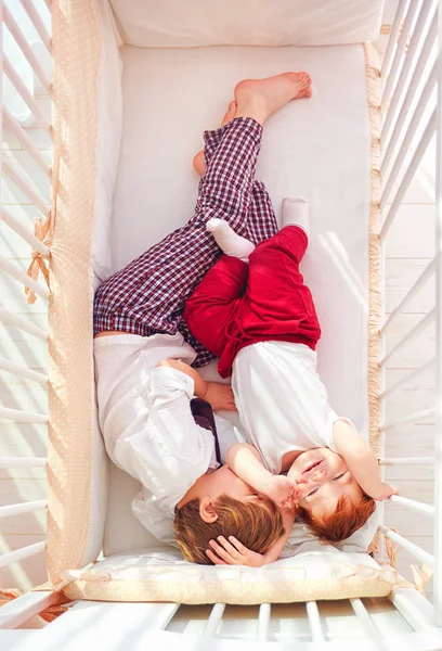 Irmãos alegres se divertindo, deitados no berço juntos — Fotografia de Stock