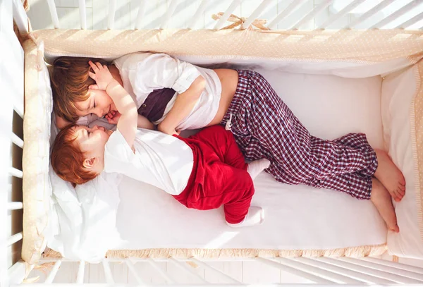 Frères gais s'amuser, couché dans la crèche ensemble — Photo