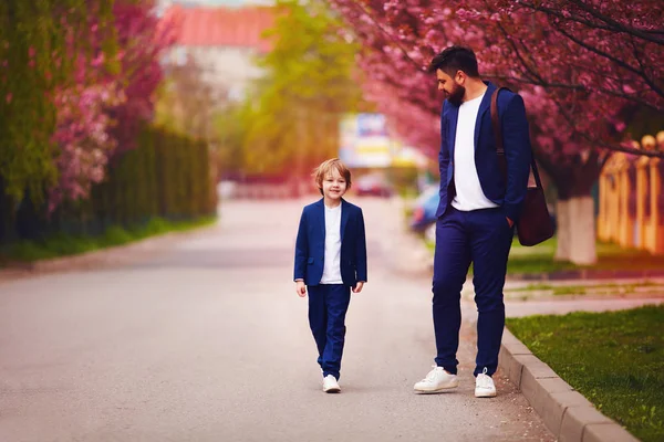 Pai feliz e filho em ternos andando ao longo da rua primavera — Fotografia de Stock