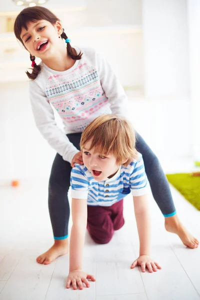 Felices niños emocionados divirtiéndose, cabalgando en la espalda en casa — Foto de Stock