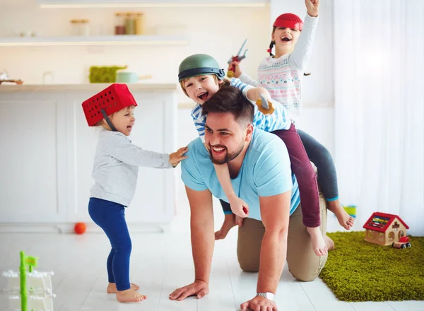 Família feliz brincando juntos em casa, montando no pai — Fotografia de Stock
