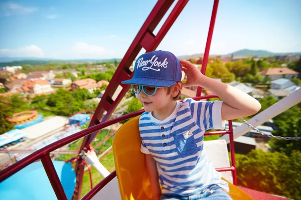 Excited kid riding on ferris wheel in amusement park — Stock Photo, Image