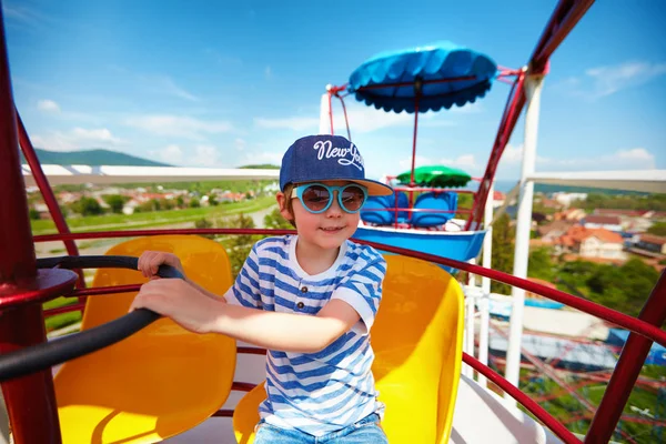 Excited kid riding on ferris wheel in amusement park — Stock Photo, Image