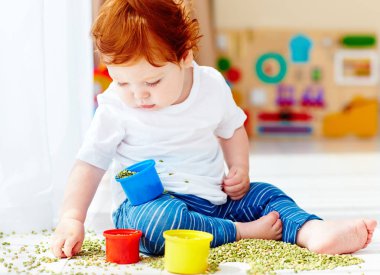 evde yeşil bezelye ile oynayarak iyi hareketliliği yeteneklerini geliştirme erkek şirin Kızıl saçlı bebek