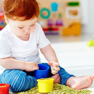 evde yeşil bezelye ile oynayarak iyi hareketliliği yeteneklerini geliştirme erkek şirin Kızıl saçlı bebek