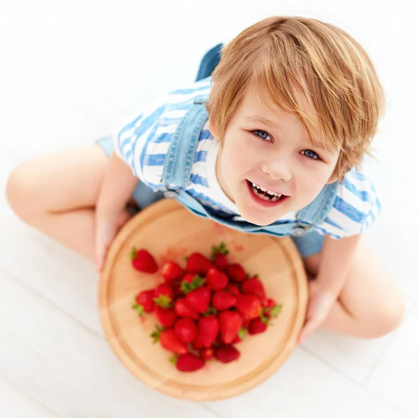 Criança feliz com uma bandeja de morangos maduros saborosos — Fotografia de Stock