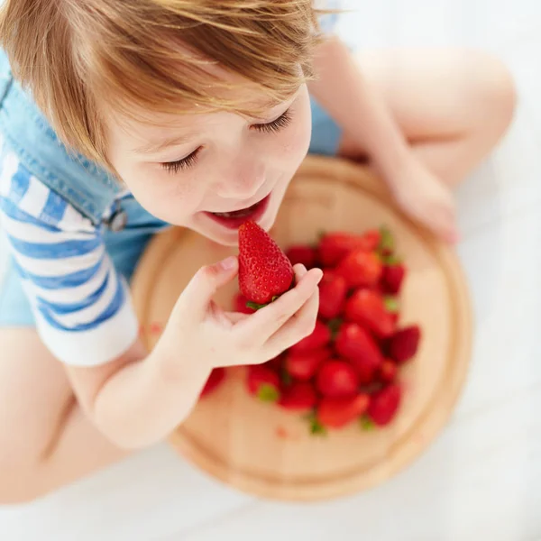 Carino bambino felice mangiare gustose fragole mature — Foto Stock