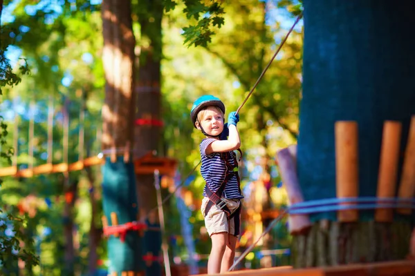 Giovane ragazzo che passa la via cavo in alto tra gli alberi, sport estremo nel parco avventura — Foto Stock