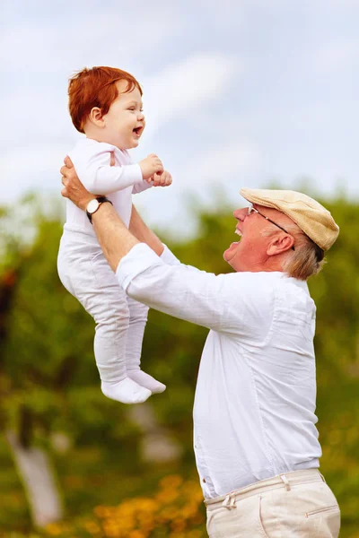 Happy děda hraje s dětskou vnuk v jarní zahradě — Stock fotografie