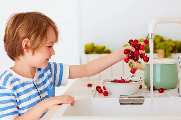 可爱的小男孩满怀的甜樱桃在厨房里的自来水下冲洗 — 图库照片