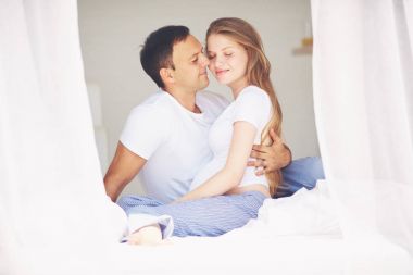 mutlu hamile çift yatak odasında sabah kucaklayan