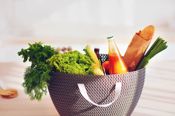 Shopping bag full of fresh food on kitchen desk — Stock Photo, Image