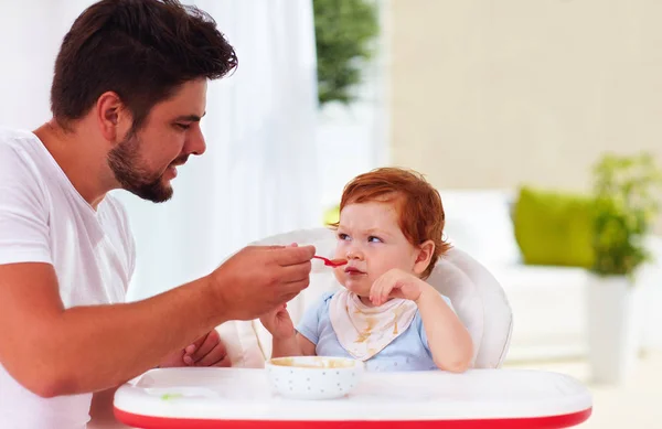 Funny toddler baby looking suspiciously on father during a meal — Stock Photo, Image