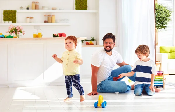 Glückliches Kleinkind beim Spielen mit Vater und Bruder zu Hause an sonnigen Sommertagen — Stockfoto