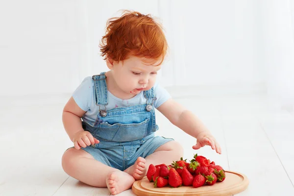 Cute ginger toddler baby tasting strawberries — Stock Photo, Image