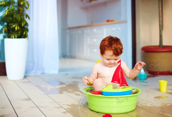 Cute redhead toddler baby having fun with water on summer terrace — Stock Photo, Image