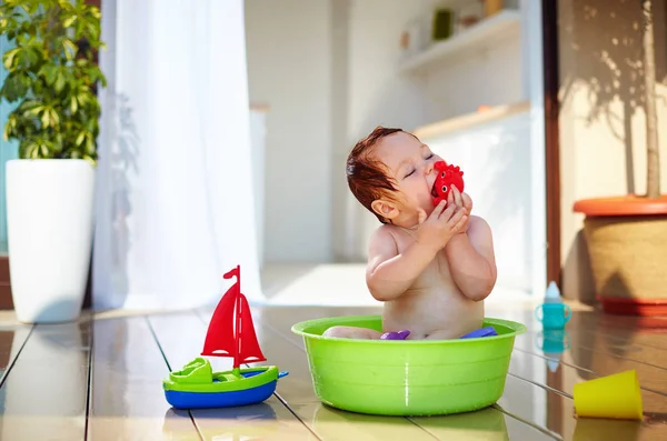 Cute redhead toddler baby having fun with water on summer terrace — Stock Photo, Image