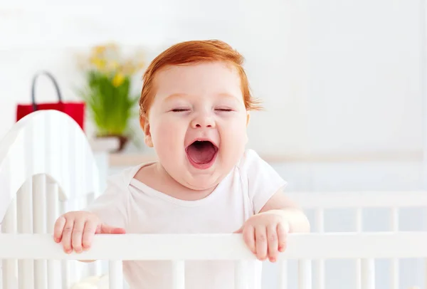 Poprtait de bebê infantil feliz bonito em pé em um berço em casa — Fotografia de Stock