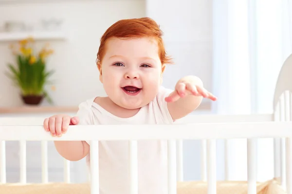 Милый счастливый младенец, стоящий дома в кроватке — стоковое фото