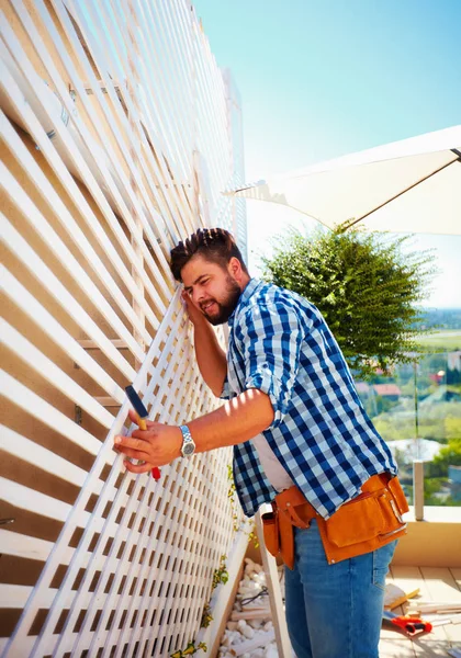 Hombre adulto joven que adorna la pared de la casa, fijando el enrejado de madera para las plantas que suben — Foto de Stock