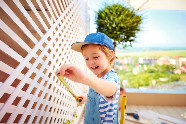 Roztomilý šťastný chlapec pomáhá zavést mřížoví na terase — Stock fotografie
