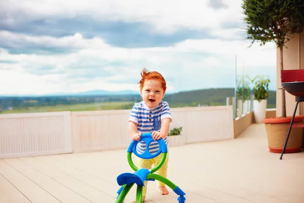 Een peuter babyjongen duwen duwen gaan winkelwagen, buitenshuis — Stockfoto