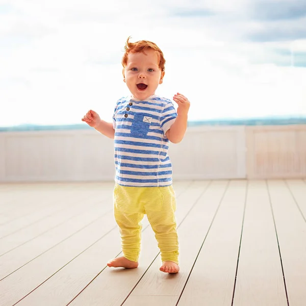 Portrait of cute redhead, one year old baby boy walking on decking — Stock Photo, Image