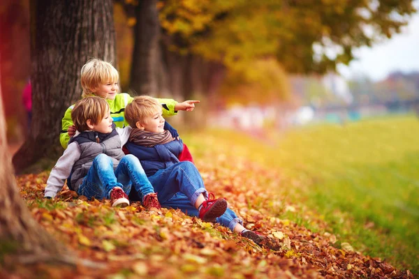 Bambini felici, amici che si divertono tra le foglie cadute nel parco autunnale — Foto Stock