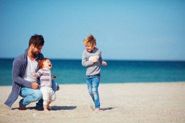 Baba ve eğleniyor, kumlu plajda çalışan oğulları