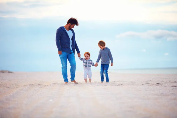 Pai feliz e filhos andando na praia de outono arenosa perto do mar — Fotografia de Stock